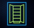 Glowing neon line Wardrobe icon isolated on brick wall background. Cupboard sign. Vector