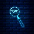 Glowing neon Magnifying glass with world map icon isolated on brick wall background. Analyzing the world. Global search