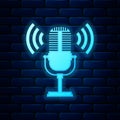 Glowing neon Microphone icon isolated on brick wall background. On air radio mic microphone. Speaker sign. Vector Royalty Free Stock Photo