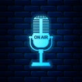 Glowing neon Microphone icon isolated on brick wall background. On air radio mic microphone. Speaker sign. Vector Royalty Free Stock Photo