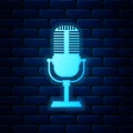 Glowing neon Microphone icon isolated on brick wall background. On air radio mic microphone. Speaker sign. Vector Royalty Free Stock Photo