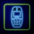 Glowing neon Old vintage keypad mobile phone icon isolated on blue background. Retro cellphone device. Vintage 90s Royalty Free Stock Photo