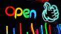 Glowing neon Open sign with a thumbs up character on a black background Royalty Free Stock Photo