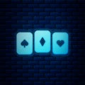 Glowing neon Playing cards icon isolated on brick wall background. Casino gambling