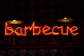 Glowing Neon red sign BARBECUE and blurred lights on black background