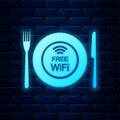 Glowing neon Restaurant Free Wi-Fi zone icon isolated on brick wall background. Plate, fork and knife sign. Vector