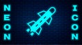 Glowing neon Rocket icon isolated on brick wall background. Vector