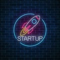 Glowing neon sign of business project startup. Business fast start symbol as a flying rocket in neon style