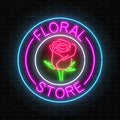 Glowing neon sign of floral store in round frames on dark brick wall background. Design of flower shop signboard.