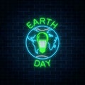 Glowing neon sign of world earth day with globe symbol and green led light bulb inside. Royalty Free Stock Photo