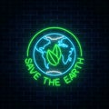 Glowing neon sign of world earth day with leaves in globe symbol and text on dark brick wall background.