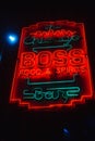 Glowing neon sign 'Boss' mounted on a brick building advertising a bar