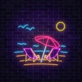 Glowing neon summer sign with chaise lounges, beach umbrella, ocean and gulls on dark brick wall background.