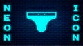 Glowing neon Swimming trunks icon isolated on brick wall background. Vector