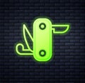 Glowing neon Swiss army knife icon isolated on brick wall background. Multi-tool, multipurpose penknife. Multifunctional
