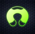 Glowing neon Travel neck pillow icon isolated on brick wall background. Pillow U-shaped. Vector