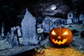 Glowing orange halloween pumpkin on old graveyard front of full moon black raven church dark night spooky horror background