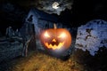 Glowing orange halloween pumpkin with scyry zombie hand on old graveyard front of full moon black raven church dark night spooky Royalty Free Stock Photo