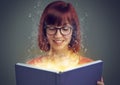 Glowing pages, book and woman with a story, fantasy and education on grey studio background. Person, reader and girl Royalty Free Stock Photo
