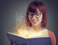 Glowing pages, book or woman with a story, glasses or education on grey studio background. Person, reader or girl with a Royalty Free Stock Photo