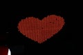 Glowing pixel red heart of LED lamps on black background