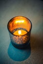 Glowing red candle set on a dark wooden table in a dimly lit room Royalty Free Stock Photo
