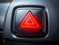 Glowing red hazard warning triangle button on a car\'s dark interior panel dashboard light Royalty Free Stock Photo