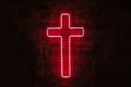 Glowing red neon cross hangs on the wall behind the bars in the dark