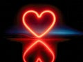 Glowing red neon heart shape with vibrant reflection on smooth black surface creating romantic and artistic visual effect in dark Royalty Free Stock Photo