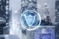 Glowing shield hologram on blurry city background. Antivirus, protection and safety concept.