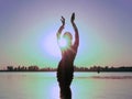 Glowing silhouette of slim woman with hands up in the air illuminated with sunshine dancing traditional tribal belly dance in fron Royalty Free Stock Photo