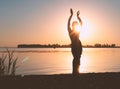 Glowing silhuette of slim woman with hands up in the air on sunset