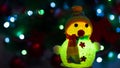 Glowing snowman on Christmas tree background with garlands Royalty Free Stock Photo