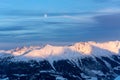 Snowy mountains during sunset in the alps with the full moon above Royalty Free Stock Photo