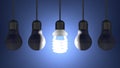 Glowing spiral light bulb among dead tungsten ones hanging on blue Royalty Free Stock Photo