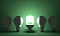 Glowing spiral light bulb in row of dead tungsten ones on green Royalty Free Stock Photo