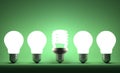 Glowing spiral light bulb in row of tungsten ones on green Royalty Free Stock Photo