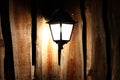 Glowing street lamp on the background of a wooden fence at night. Light permeates the darkness. Street lighting. Creating a cozy a Royalty Free Stock Photo