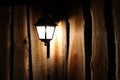 Glowing street lamp on the background of a wooden fence at night. Light permeates the darkness. Street lighting. Creating a cozy a Royalty Free Stock Photo