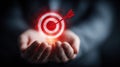 Glowing target with an arrow held in hands, representing goals and success. Royalty Free Stock Photo