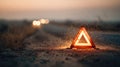 Glowing warning triangle on an empty road at sunset with sparks flying Royalty Free Stock Photo