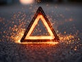Glowing warning triangle with sparks and embers on a dark road surface Royalty Free Stock Photo
