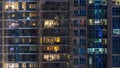 Glowing windows in multistory modern glass residential building light up at night timelapse. Royalty Free Stock Photo