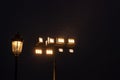 A glowing wrought-iron lamp on a lamppost and luminous industrial lamps at night  against the dark sky  illuminate with a contour Royalty Free Stock Photo