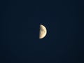 Glowing yellow half moon in a dark blue night sky