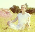 Glowing young yoga woman contemplating to meditate, sunny retro effects