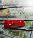 GLP-1 label and semaglutide molecule structure on assorted one hundred dollar bills Royalty Free Stock Photo