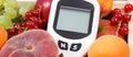 Glucometer for measuirng sugar level and fruits in wooden box as healthy snack or dessert containing natural vitamins Royalty Free Stock Photo