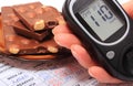 Glucometer in hand and portion of chocolate on medical form