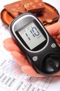 Glucometer in hand and portion of chocolate on medical form